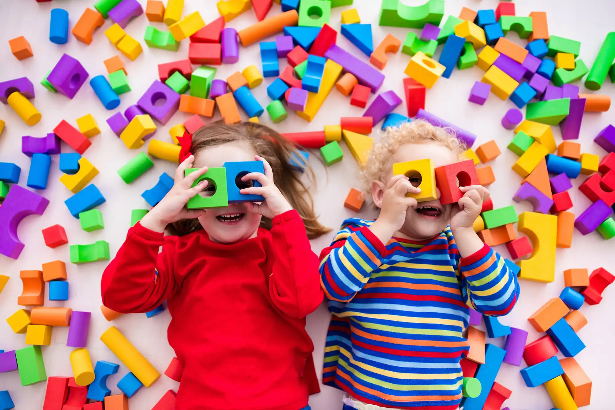 two girls laying on a floor with scattered blocks