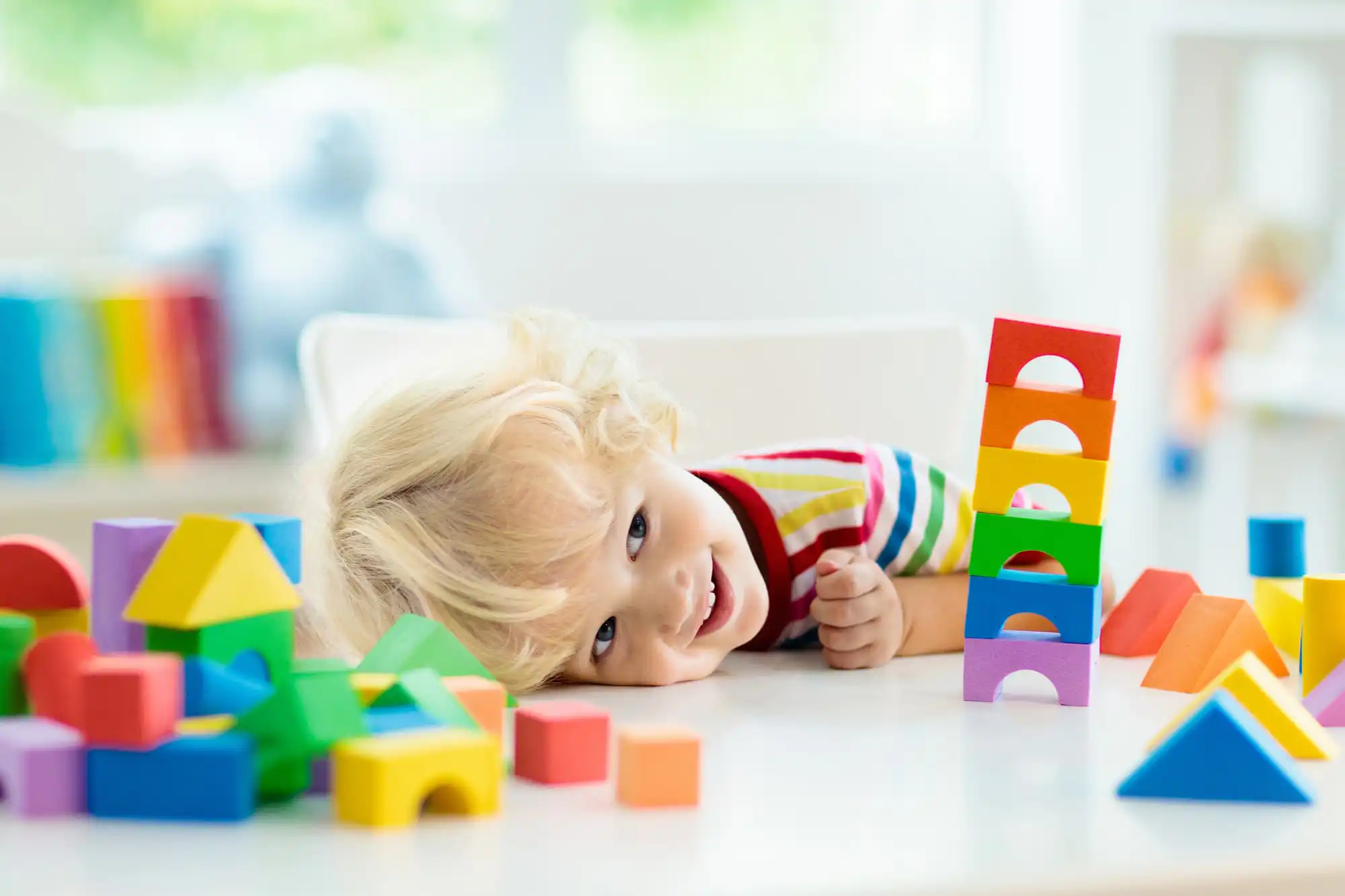 a kid smiling while laying his head on the table